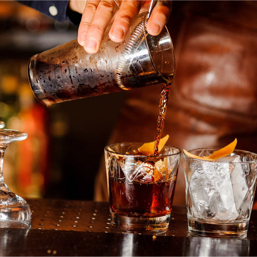 old fashioned cocktail being strained and poured